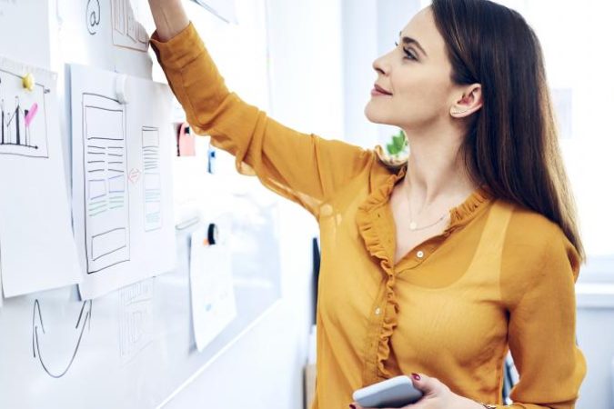 smiling-businesswoman-taking-notes-on-whiteboard-i-2022-01-06-21-36-20-utc